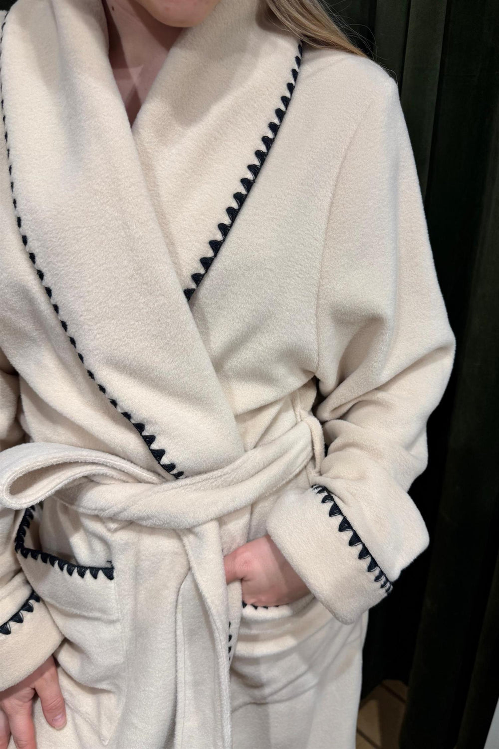 Pluto Quinta lang morgenkåpe i beige fleece med svarte kontrastdetaljer på krage og mansjetter.