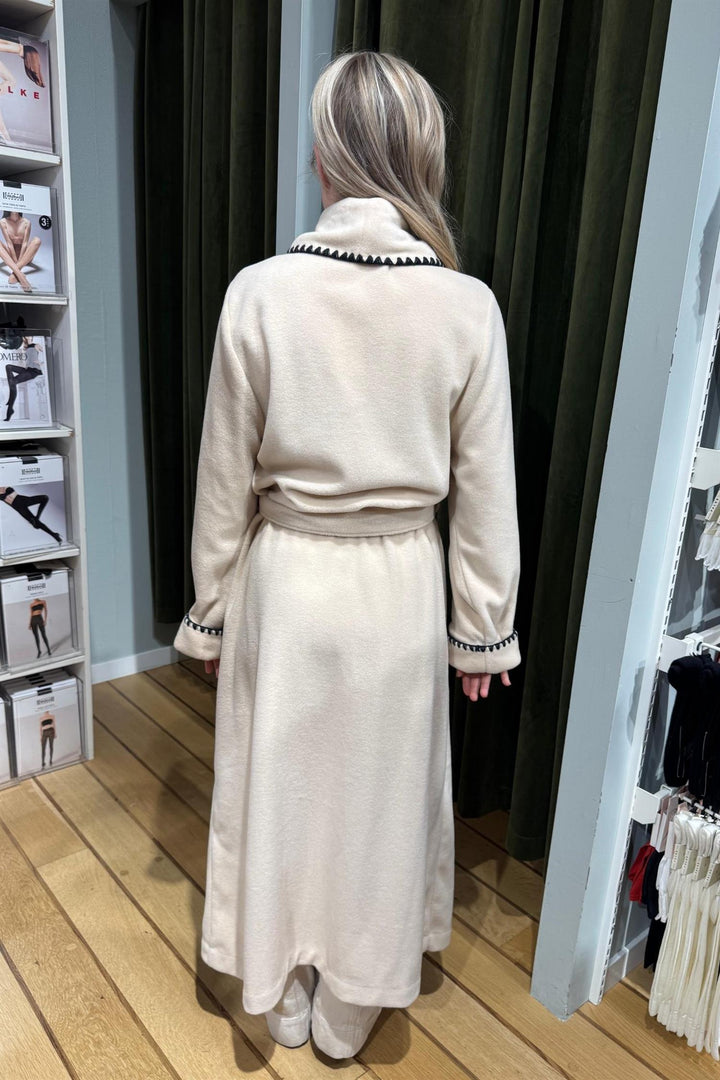 Pluto Quinta lang morgenkåpe i beige fleece med svarte kontrastdetaljer på krage og mansjetter.